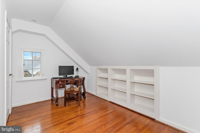 office with hardwood / wood-style flooring, vaulted ceiling, and built in features