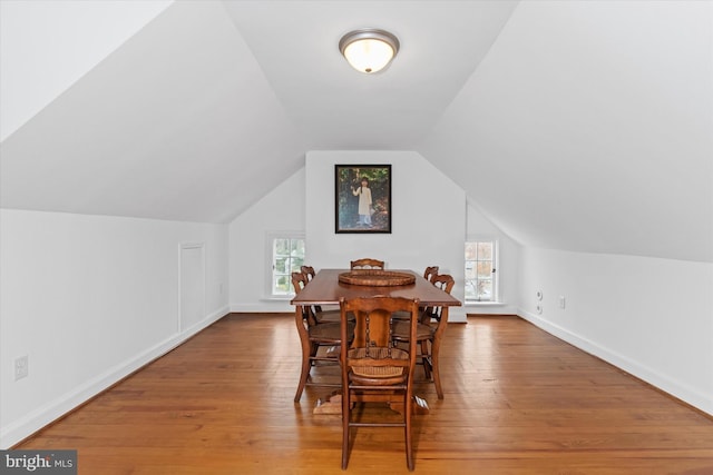 dining room featuring hardwood / wood-style flooring and vaulted ceiling