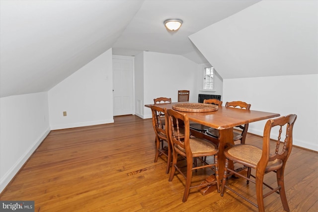 dining area with hardwood / wood-style flooring, lofted ceiling, and radiator heating unit