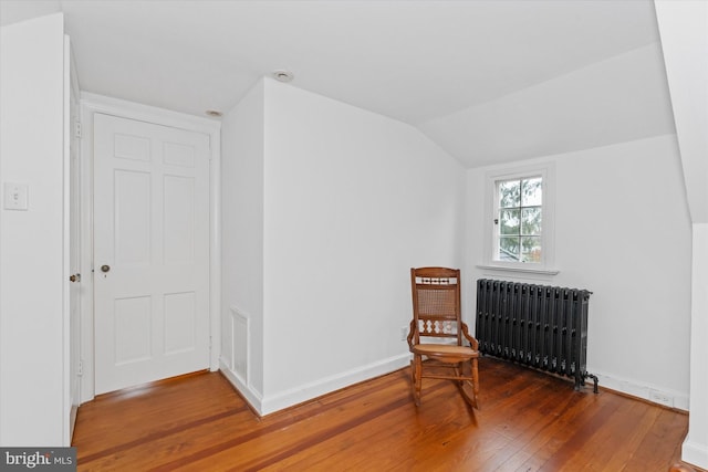 sitting room with lofted ceiling, radiator, and hardwood / wood-style floors