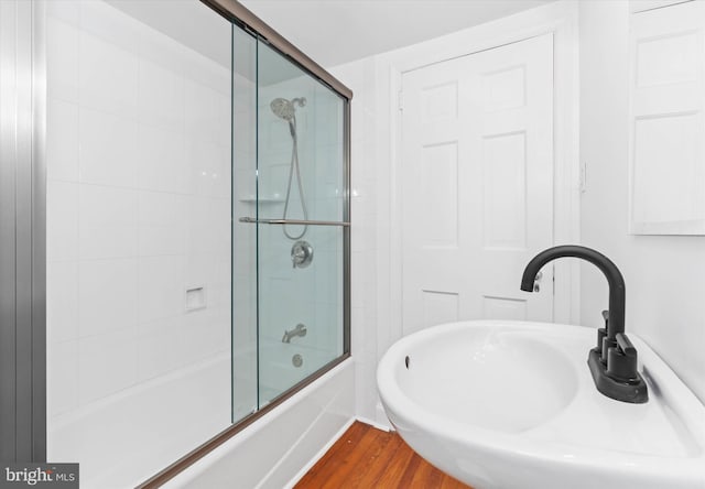 bathroom with sink, hardwood / wood-style floors, and enclosed tub / shower combo