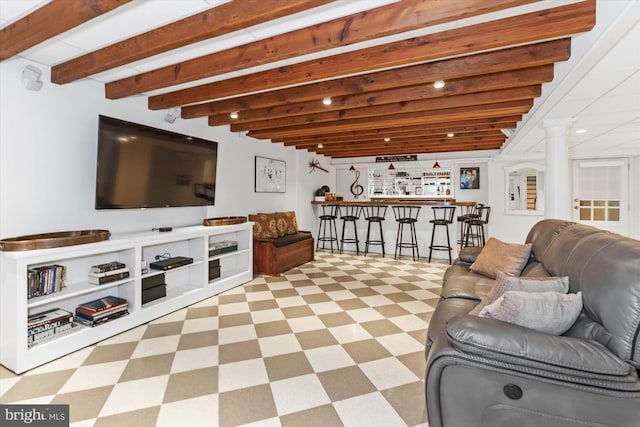 living room with bar, beam ceiling, and decorative columns