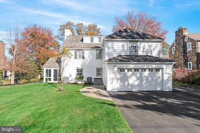 view of property featuring a garage, a front yard, and central AC unit