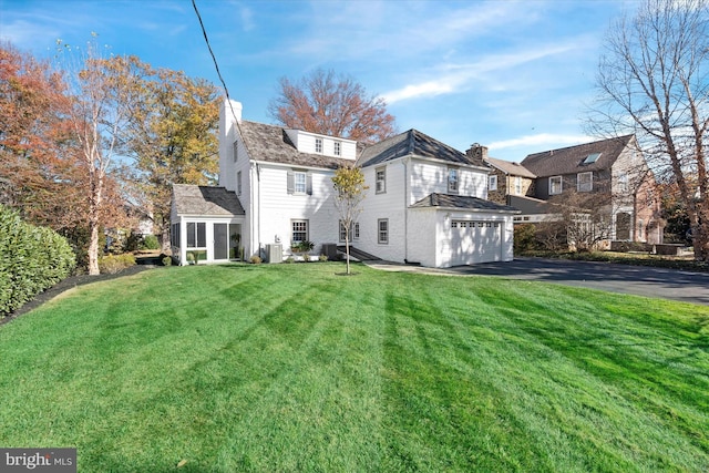 back of property with a garage, a yard, and central AC