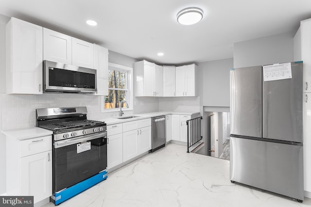 kitchen featuring tasteful backsplash, appliances with stainless steel finishes, sink, and white cabinets