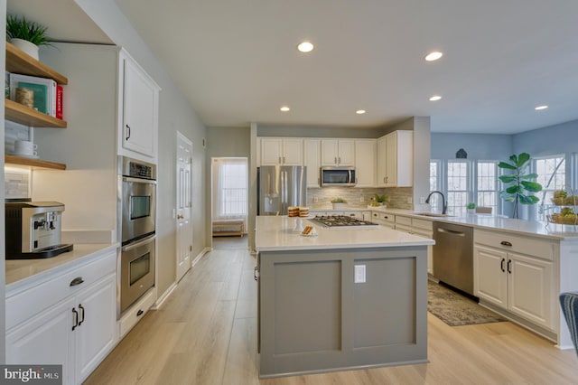 kitchen featuring sink, light hardwood / wood-style flooring, appliances with stainless steel finishes, white cabinetry, and a kitchen island