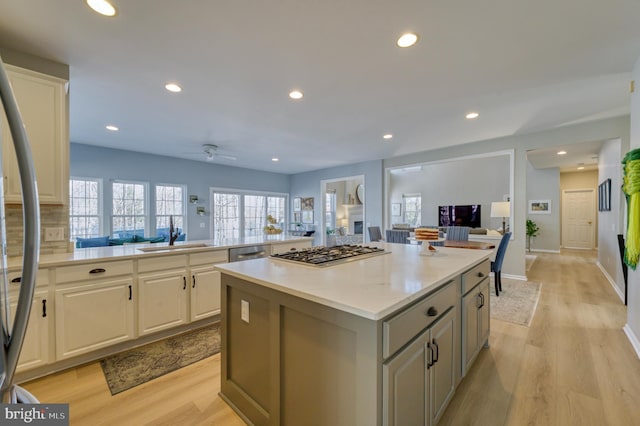 kitchen featuring sink, light hardwood / wood-style flooring, appliances with stainless steel finishes, white cabinets, and a kitchen island