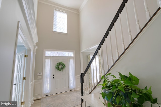 foyer with a towering ceiling and ornamental molding