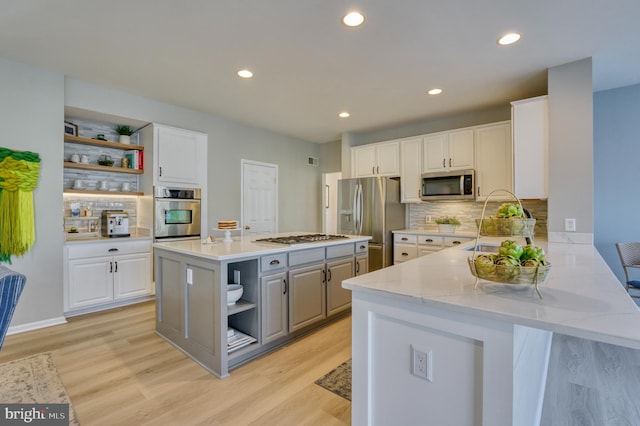 kitchen featuring stainless steel appliances, kitchen peninsula, a kitchen island, and white cabinets