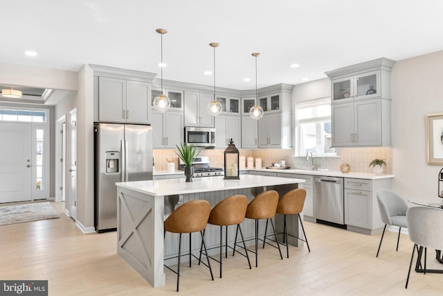 kitchen featuring a breakfast bar area, hanging light fixtures, backsplash, stainless steel appliances, and a kitchen island