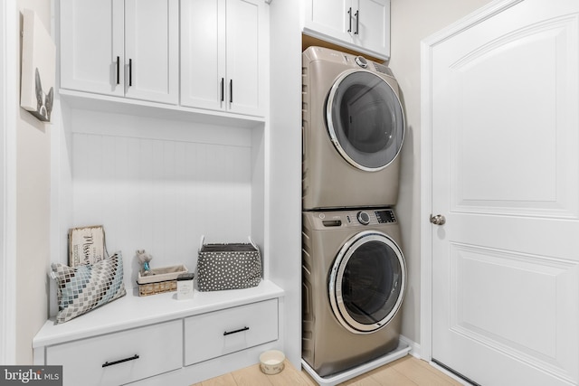 washroom featuring cabinets and stacked washer / dryer