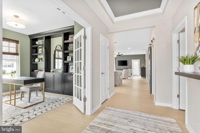 hall with crown molding, a barn door, and light wood-type flooring