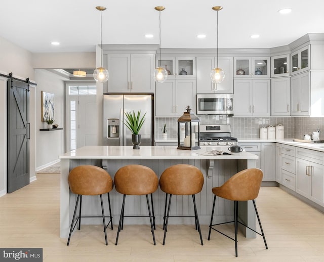 kitchen featuring a center island, pendant lighting, stainless steel appliances, a barn door, and backsplash