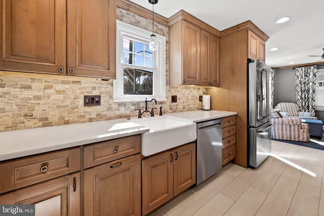 kitchen with a sink, decorative light fixtures, tasteful backsplash, stainless steel appliances, and brown cabinetry