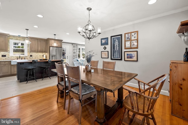 dining room featuring baseboards, light wood-type flooring, and ornamental molding