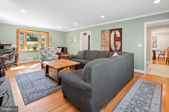 living room featuring crown molding, light wood-style flooring, and visible vents