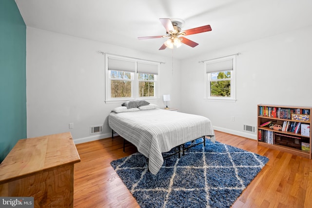 bedroom with visible vents, baseboards, and wood finished floors