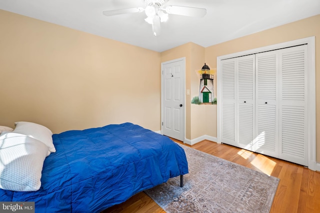 bedroom with a closet, baseboards, wood finished floors, and a ceiling fan