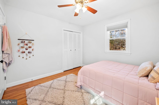 bedroom with a closet, ceiling fan, baseboards, and wood finished floors