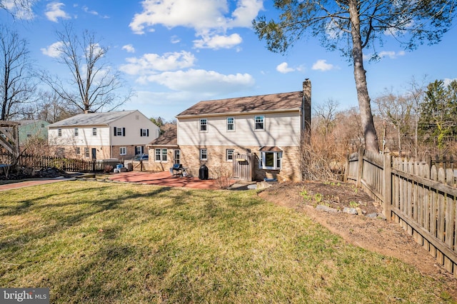 rear view of house with fence, a yard, a wooden deck, brick siding, and a chimney