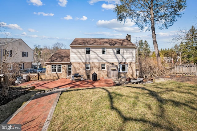 rear view of property with a yard, fence, brick siding, and a chimney