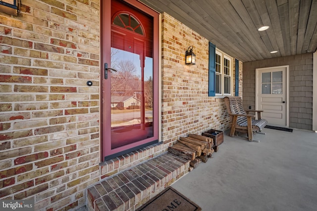 property entrance featuring covered porch and brick siding