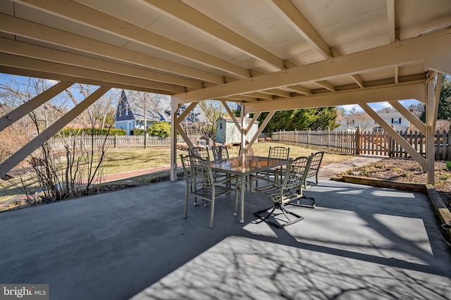 view of patio / terrace featuring an outbuilding, outdoor dining space, a shed, and a fenced backyard