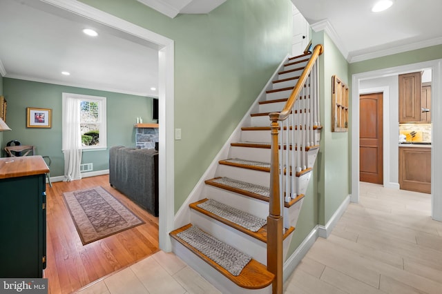 staircase with visible vents, crown molding, baseboards, recessed lighting, and wood finished floors