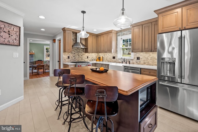 kitchen with backsplash, crown molding, a breakfast bar area, appliances with stainless steel finishes, and wall chimney exhaust hood