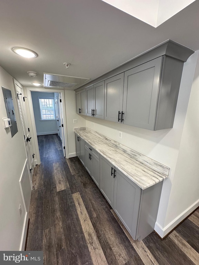 interior space with dark hardwood / wood-style floors, gray cabinetry, and light stone counters