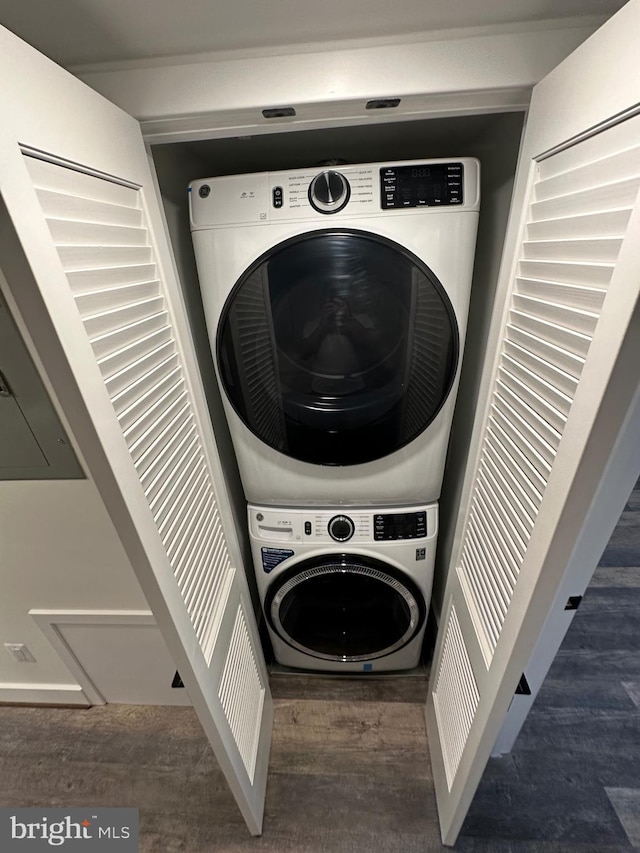 washroom with stacked washer and dryer and dark wood-type flooring