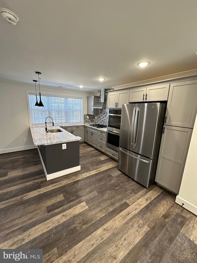 kitchen featuring gray cabinets, pendant lighting, light stone counters, stainless steel appliances, and wall chimney exhaust hood