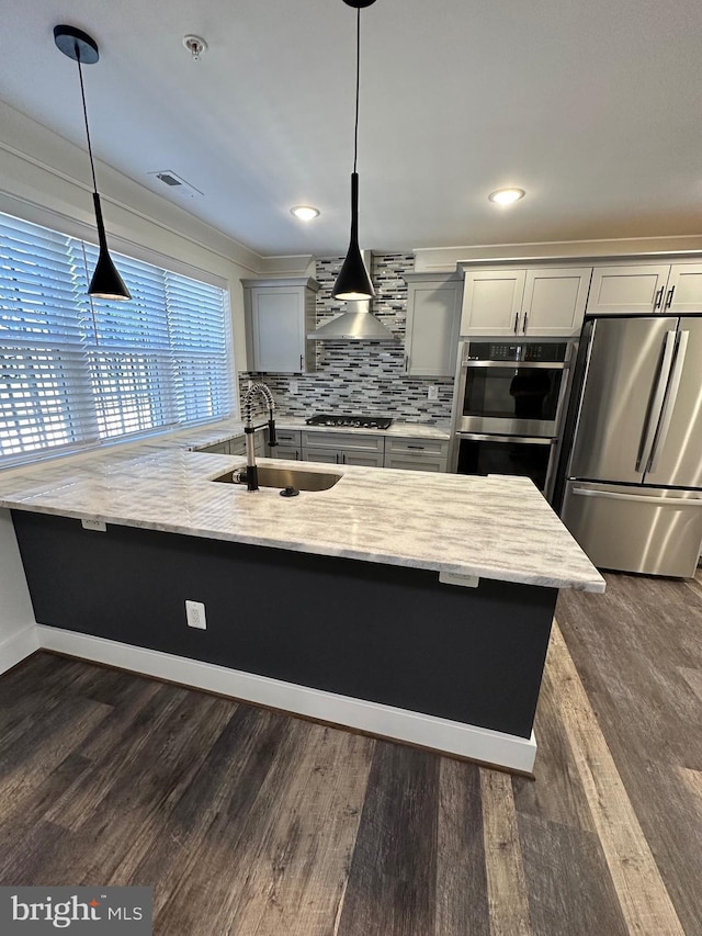 kitchen with light stone countertops, appliances with stainless steel finishes, sink, and decorative light fixtures