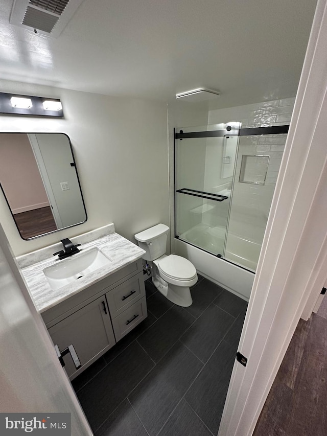 full bathroom featuring toilet, vanity, and shower / bath combination with glass door