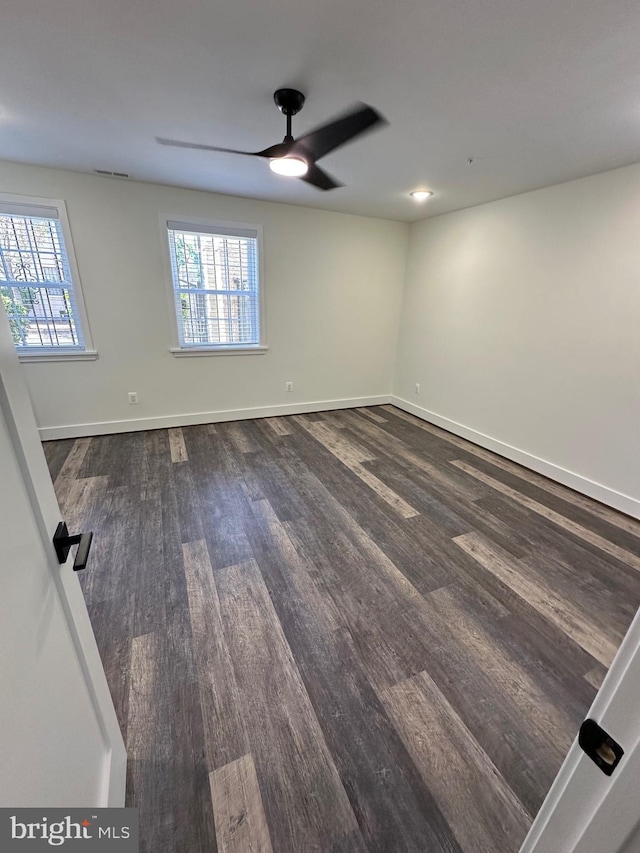 spare room featuring dark wood-type flooring, ceiling fan, and plenty of natural light