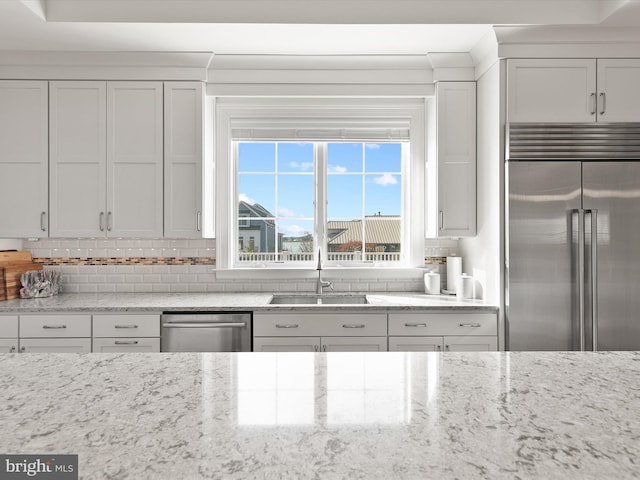 kitchen with sink, white cabinetry, tasteful backsplash, stainless steel appliances, and light stone countertops