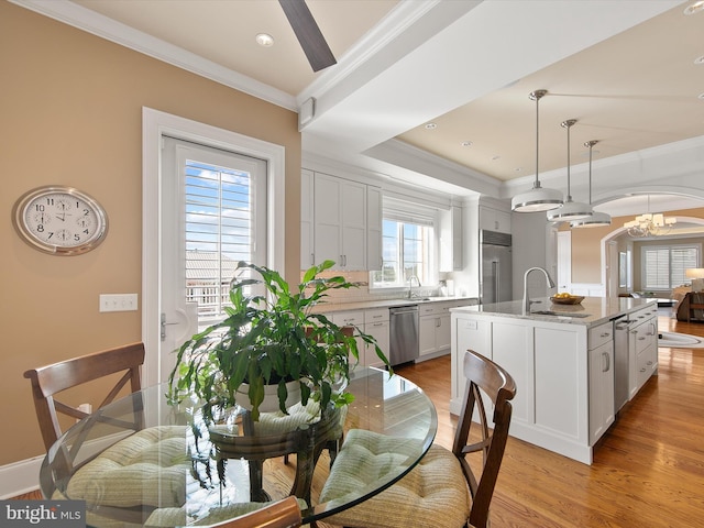 dining area featuring a chandelier, ornamental molding, light hardwood / wood-style floors, and sink