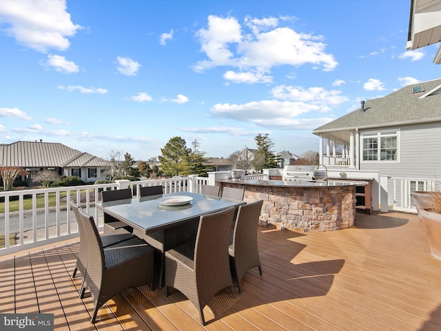 deck featuring an outdoor kitchen, a grill, and exterior bar