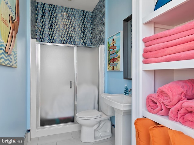 bathroom with tile patterned floors, toilet, and a shower with shower door