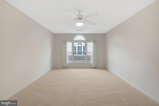 empty room featuring ceiling fan, visible vents, baseboards, and light colored carpet