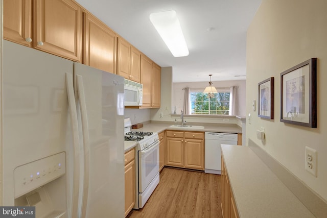 kitchen with decorative light fixtures, light countertops, light brown cabinetry, a sink, and white appliances