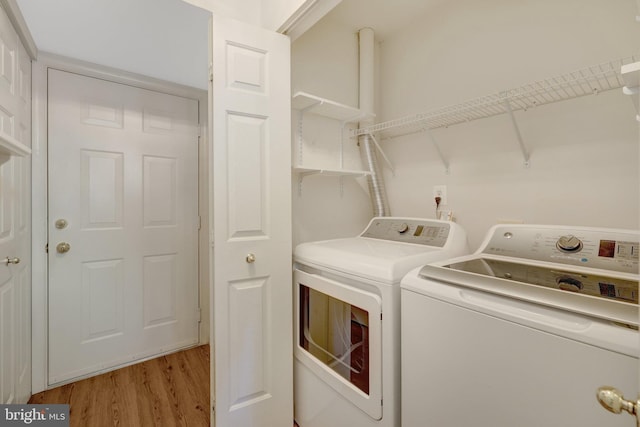 clothes washing area featuring light wood-type flooring, laundry area, and separate washer and dryer