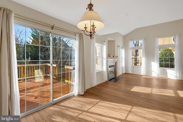 doorway to outside featuring vaulted ceiling, a fireplace with flush hearth, and wood finished floors