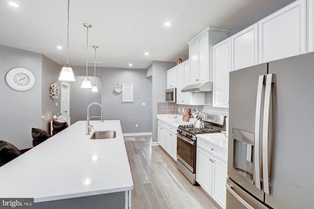 kitchen with sink, white cabinetry, stainless steel appliances, an island with sink, and decorative light fixtures