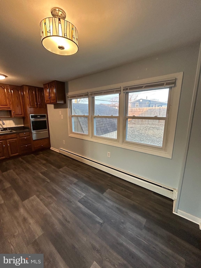 kitchen featuring baseboard heating, dark hardwood / wood-style floors, oven, and sink