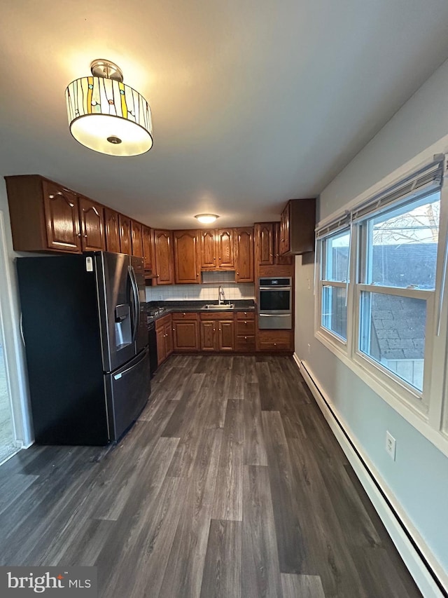 kitchen with sink, stainless steel fridge, dark hardwood / wood-style floors, and a baseboard radiator