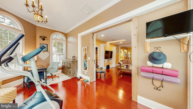 exercise room featuring an inviting chandelier, visible vents, crown molding, and wood finished floors