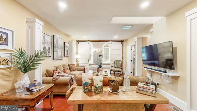 living area with decorative columns, baseboards, visible vents, wood finished floors, and recessed lighting