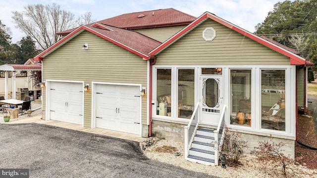 view of front facade featuring driveway, entry steps, a garage, and roof with shingles