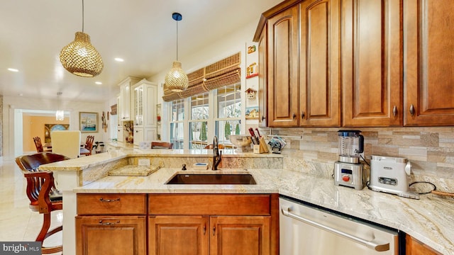 kitchen with dishwasher, brown cabinets, a sink, and pendant lighting